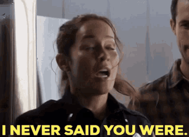 a woman in a police uniform is standing next to a man and saying `` never said you were '' .