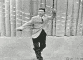 a black and white photo of a man dancing on a stage .