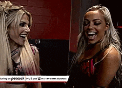 two women are laughing together in a room and looking at each other .