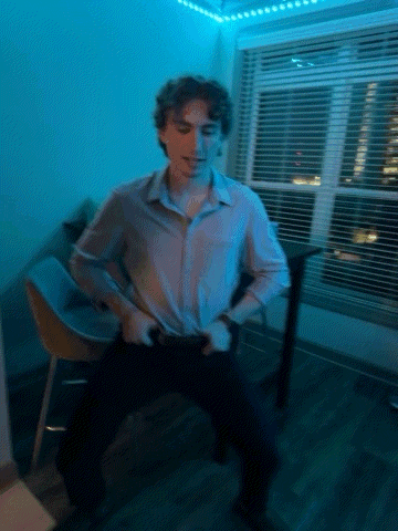 a man in a white shirt is dancing in a room with blue lights behind him .