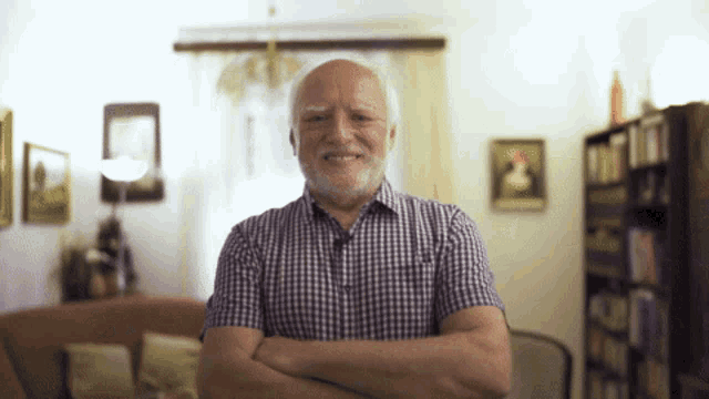 an elderly man with his arms crossed smiles for the camera