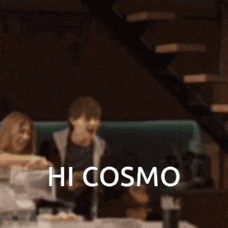 a blurred image of people sitting at a table with the words hi cosmo on the bottom right