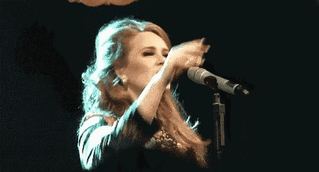 a woman is singing into a microphone on stage