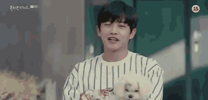 a young man is holding a small white dog in his arms .