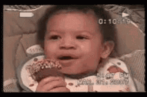 a baby is sitting in a high chair eating a donut .