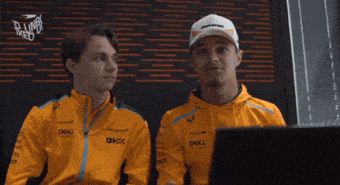 a man wearing a mclaren cap sits next to another man