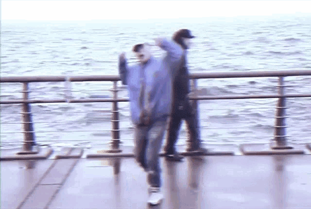 a blurry picture of two people standing on a pier near the water .