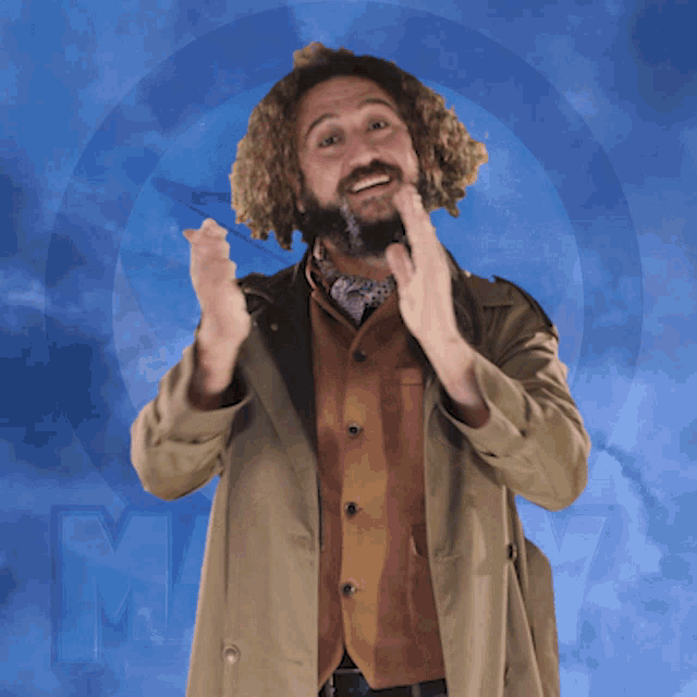 a man with curly hair and a beard is wearing a trench coat and a brown vest
