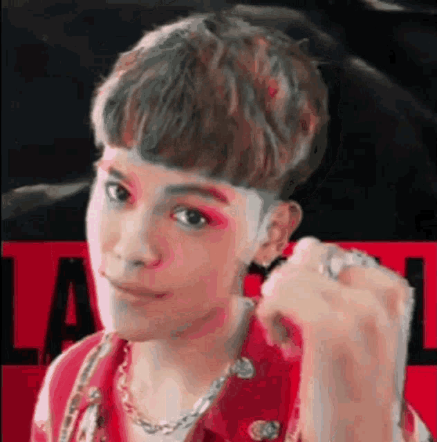 a close up of a person wearing a red vest and a necklace .