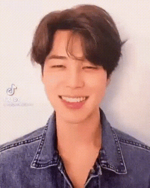 a close up of a person wearing a denim jacket smiling .