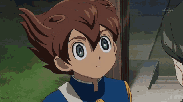 a boy in a blue jacket is making a funny face in front of a tv screen that says bs japan on it