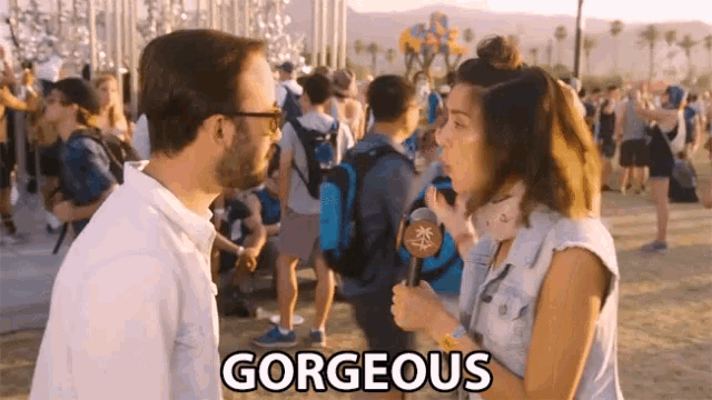a woman is holding a microphone in front of a crowd and the word gorgeous is above her