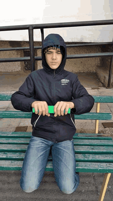 a boy sitting on a bench wearing a jacket that says supreme