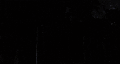 a black and white photo of an elderly man in a dark room looking at the camera .