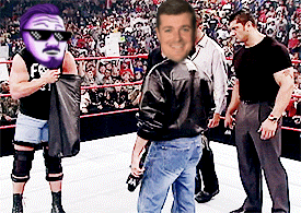 a man in a black shirt with the letter f on it is standing in a wrestling ring