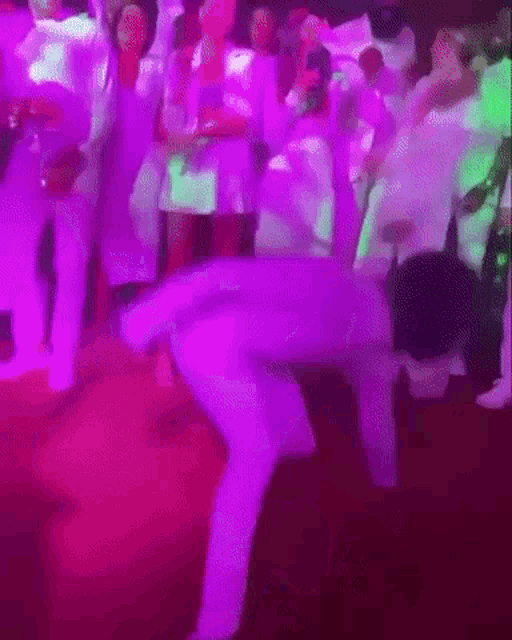 a man is dancing on the floor in front of a crowd at a party .