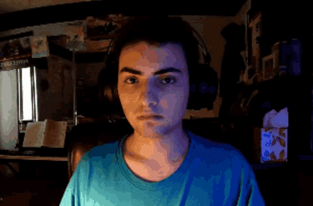 a man wearing headphones looks at the camera with a box of kleenex in front of him