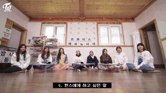 a group of girls sit in a room with a sign that says twice on it