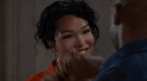 a man is hugging a woman who is smiling and looking at the camera .