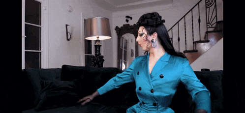 a woman in a blue suit is sitting on a couch