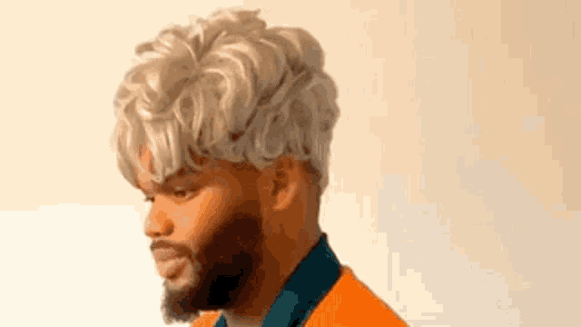 a man with a beard and blonde hair is wearing a wig and an orange shirt .