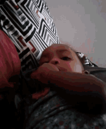 a baby is laying on a bed with a black and white striped pillow in the background .