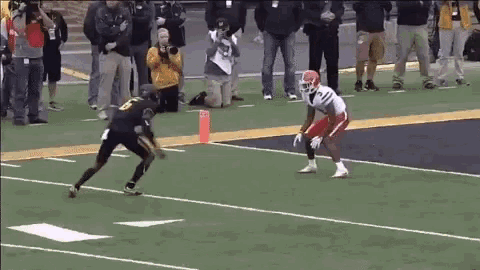 a football player in a black and white uniform is being tackled by a player in a red uniform .