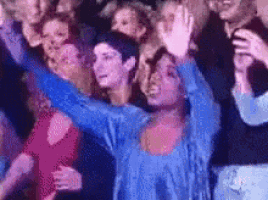 a woman in a blue shirt is dancing in a crowd
