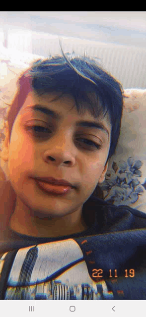 a young boy laying on a couch with the date 22 11 19 on the bottom of the screen