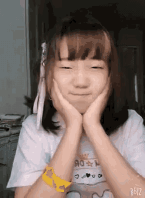 a girl with a yellow bracelet on her wrist is making a funny face with her hands on her face .