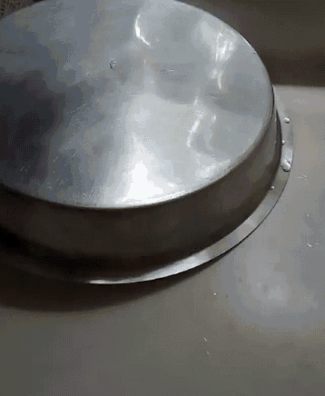 a metal tray is sitting on a white surface with water drops on it