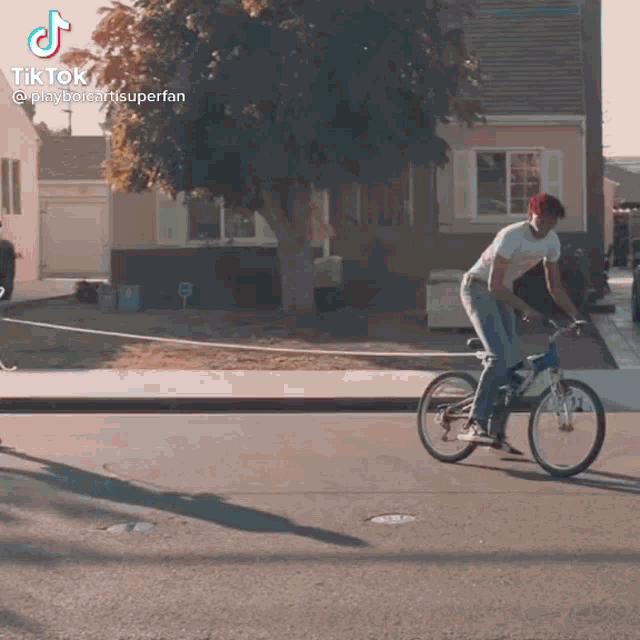 a man is riding a bike down a street while wearing a hat .