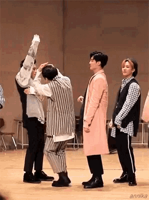a group of young men are standing next to each other on a stage and dancing .