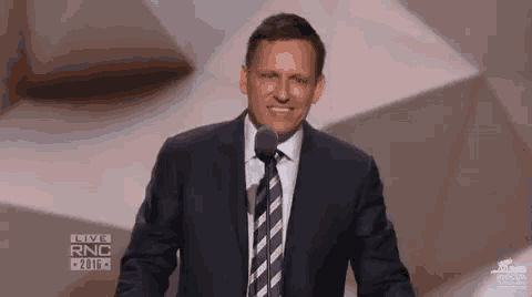 a man in a suit and tie is talking into a microphone .