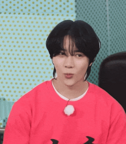 a young man wearing a red sweater is making a funny face