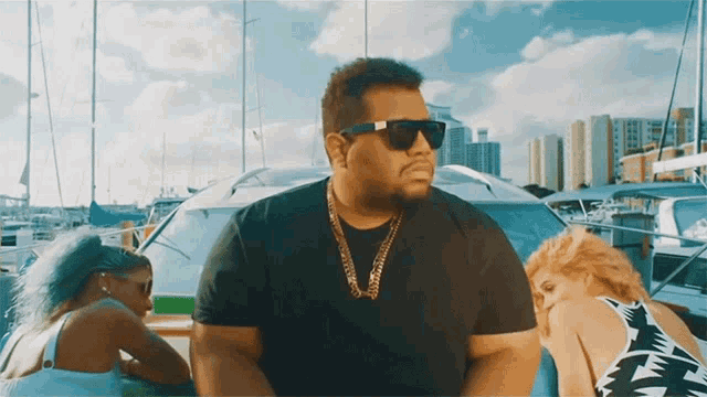 a man wearing sunglasses and a gold chain is sitting on a boat