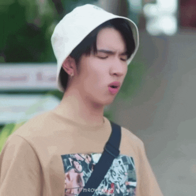 a young man wearing a hat and a t-shirt is making a face .