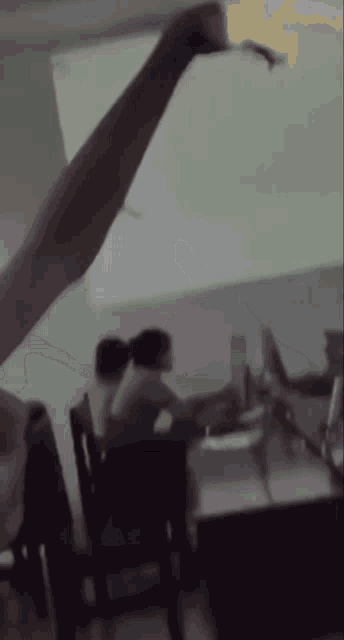 a blurry picture of people sitting at desks in front of a large screen