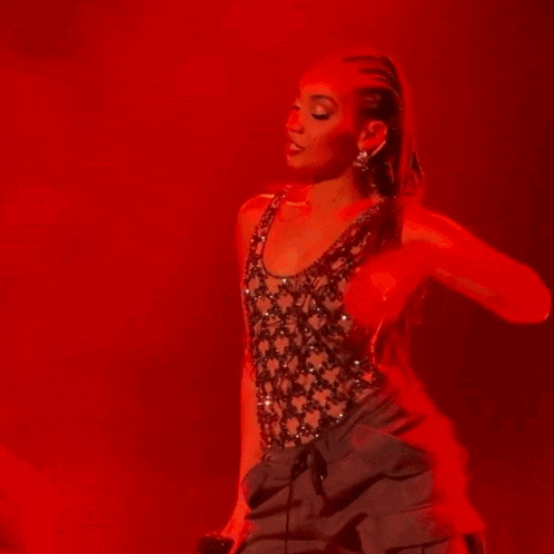 a woman with braids is dancing on a stage wearing a black top and black shorts .
