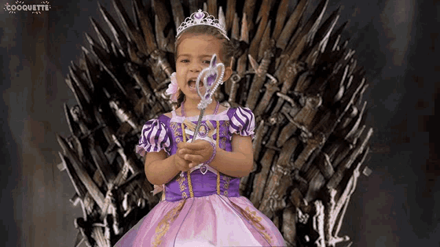 a little girl in a princess dress is sitting on a throne holding a wand