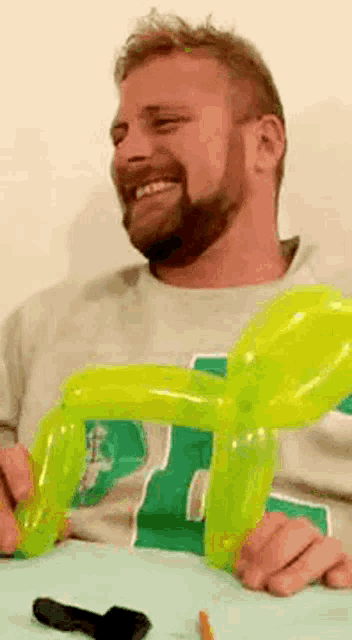 a man with a beard is sitting at a table holding a yellow balloon .