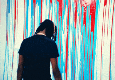 a man in a black shirt is standing in front of a wall with red and blue paint
