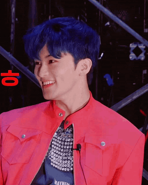 a man with blue hair wearing a red jacket and a shirt that says mayhem