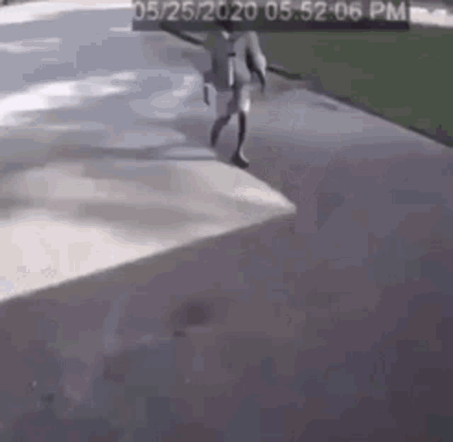a man is walking down a sidewalk with a skateboard .