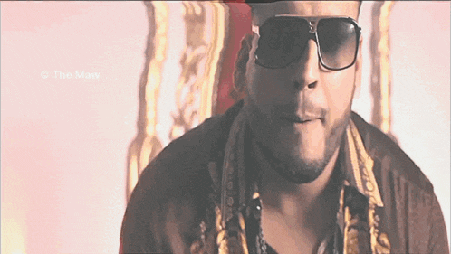 a man wearing sunglasses looks at the camera with the watermark the maw