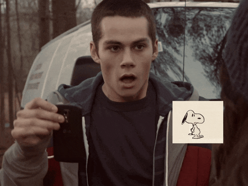 a man is taking a picture of a snoopy drawing on a piece of paper