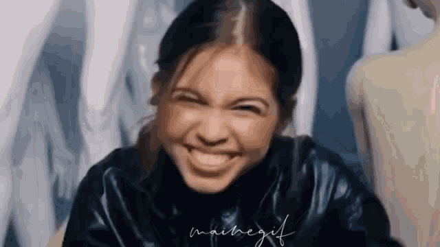 a woman in a black leather jacket is making a funny face and smiling .