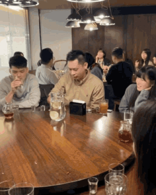 a group of people are sitting around a table drinking drinks