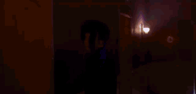 a man is standing in a doorway in front of a purple background with a galaxy in the background .