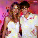 a woman in a white dress is standing next to a man in a white shirt .